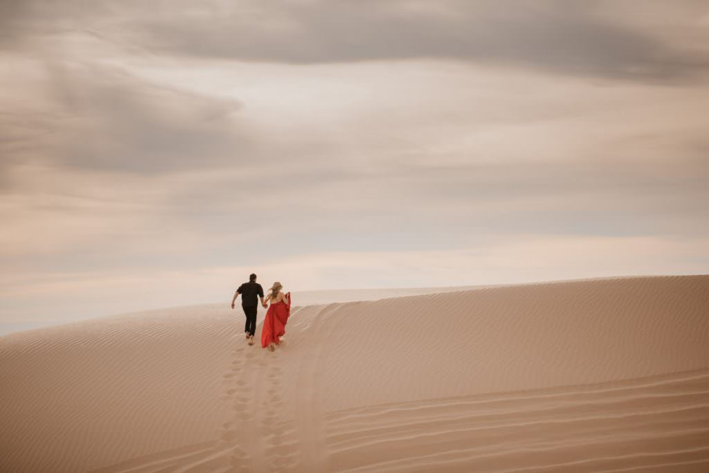 glamis sand dunes engagement session running towards the sun